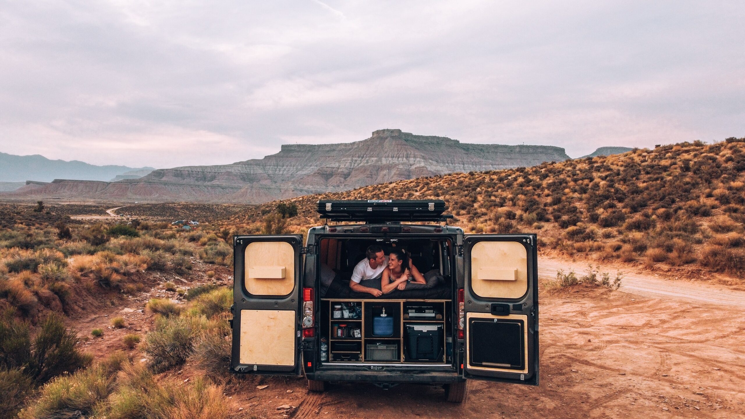 Couple in the back of a campervan off the side of a dirt road