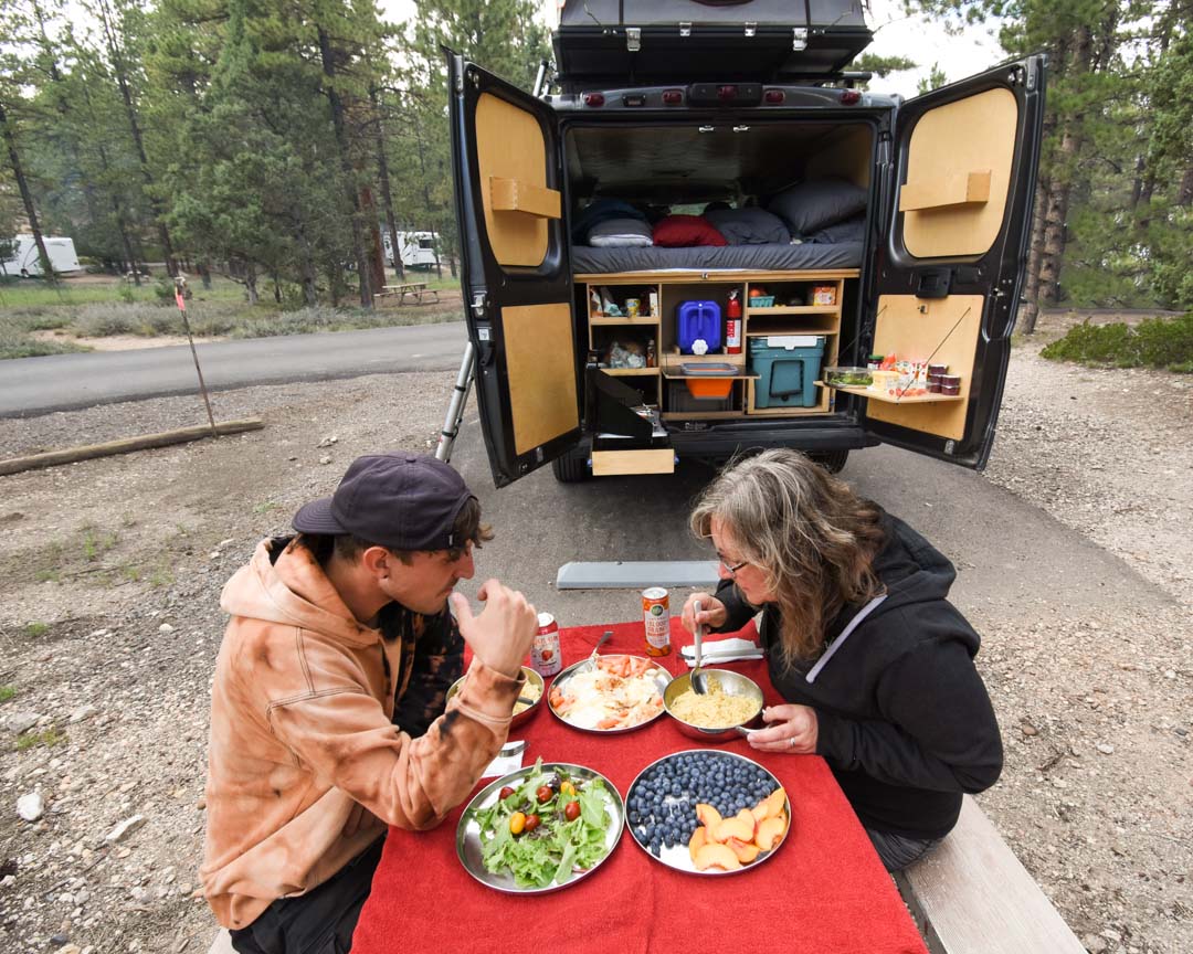 Two people having a meal with a van in the background