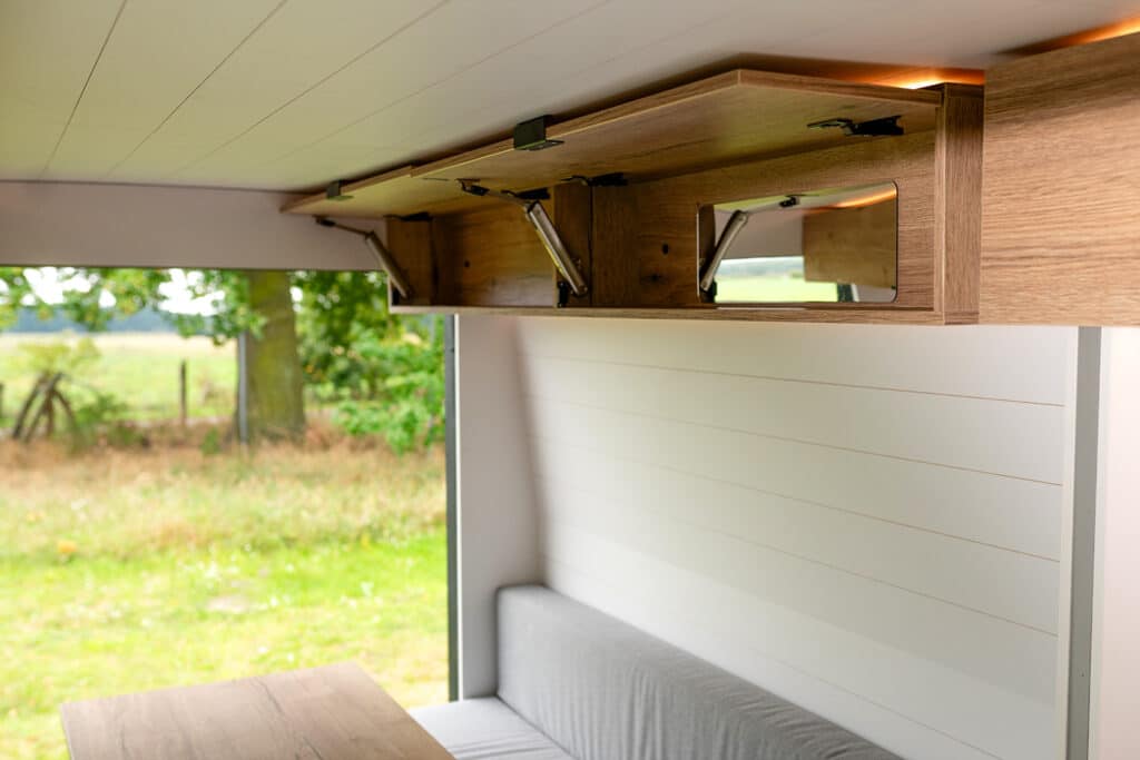 Overhead storage cabinets with built-in mirror inside The Biggie campervan